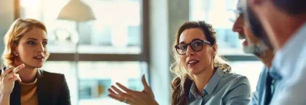 Three business professionals discussing RFP software solutions during a meeting.
